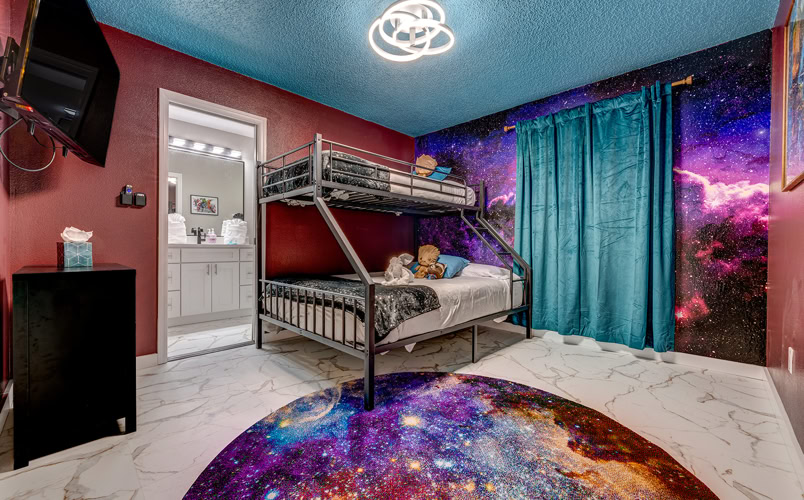 Galaxy-Themed Bunk Room with Private Bath – Kissimmee Vacation Rental Vibrant space-themed kids bunk bedroom with starry wall mural and ensuite bathroom at Marble Studios Florida in Kissimmee