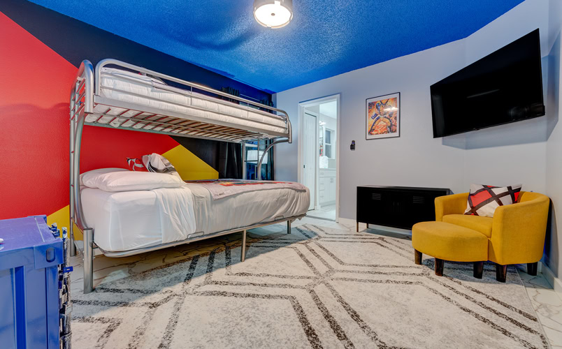 Deadpool & Wolverine Bunk Room – Kissimmee Family Vacation Rental Colorful superhero-themed bunk bedroom with TV and private bath at Marble Studios Florida in Kissimmee